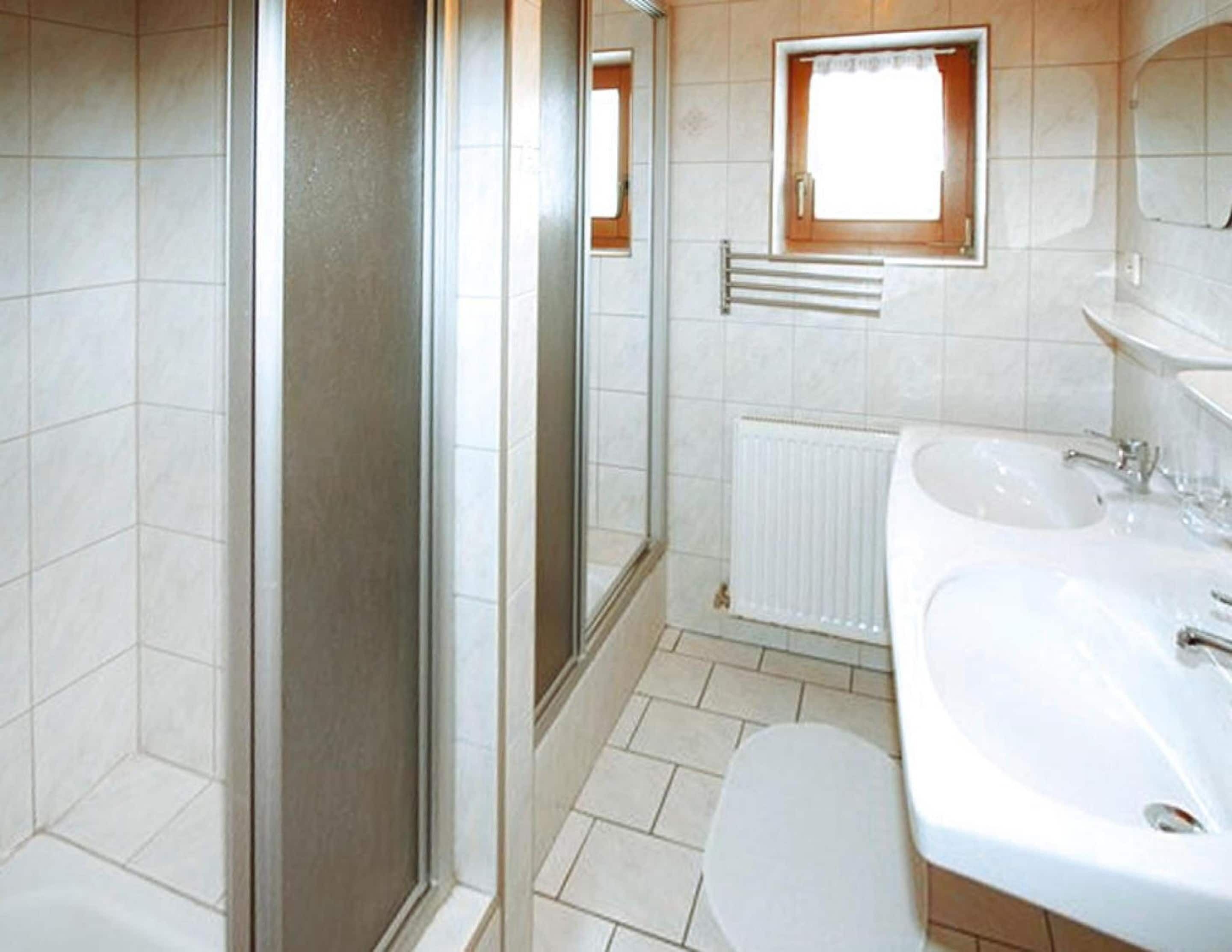 Un baño con ducha, inodoro, lavabo y ventana.
