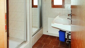 Ein Badezimmer mit Dusche, Waschbecken und Fenster.