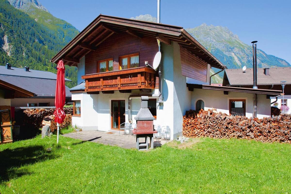 A chalet-style building with a wooden balcony, a chimney, and a view of mountains.