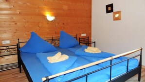 Ein Zimmer mit Holzwänden, einem Bett, Kissen und einer Wandleuchte.
