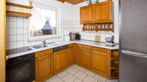 Eine Küche mit Holzausstattung, einem Edelstahlkühlschrank und einem Fenster mit Blick auf ein Gebäude.