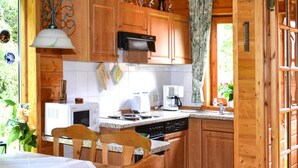 Une cuisine chaleureuse avec des meubles en bois, une table à manger avec des chaises, un four à micro-ondes, une machine à café et une cuisinière.
