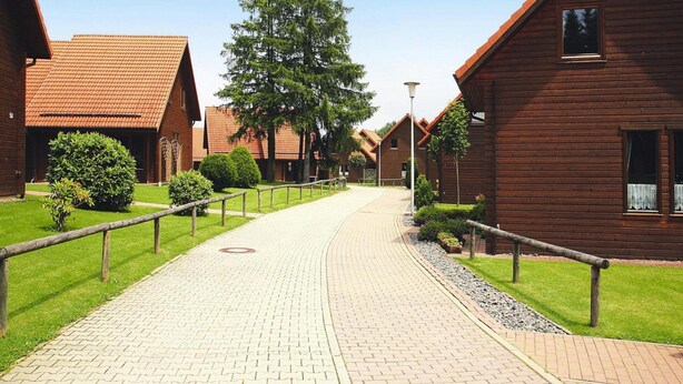 Un sentier menant à des cabanes en bois, avec un ciel dégagé au-dessus.