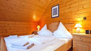 Une chambre à coucher dans un chalet en bois, avec un lit, des oreillers, une table de chevet avec une lampe et un tableau encadré au mur.