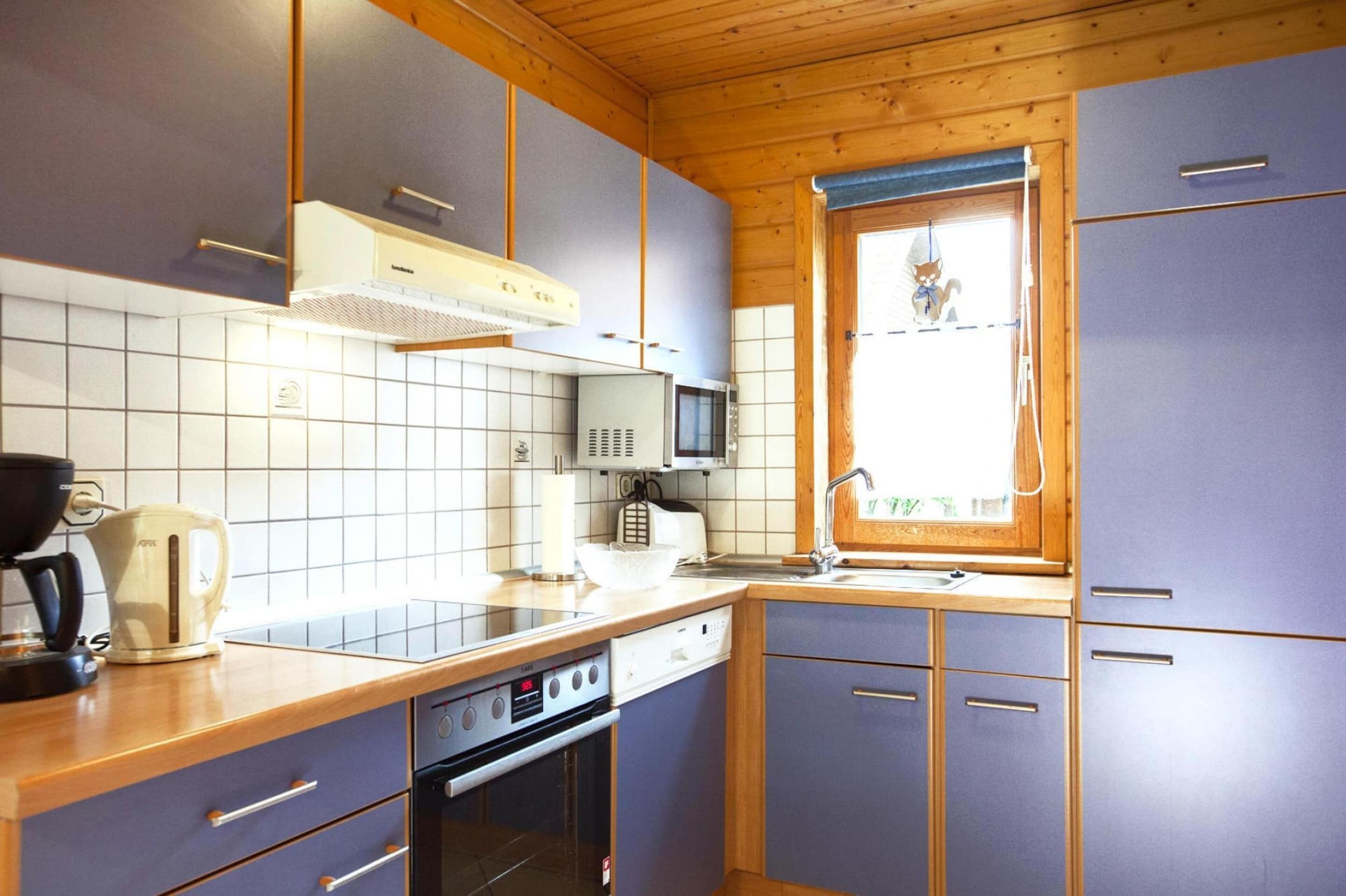 A compact kitchen with wooden cabinets, a microwave, a toaster, and a sink.