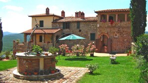Un bâtiment en pierre doté d’une cour, d’une fontaine et d’un espace extérieur aménagé pour s’asseoir.