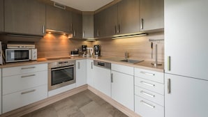A modern kitchen with stainless steel appliances, wooden cabinets, and a light-colored countertop. - Apartment in Friedrichskoog-spitze With Parking Space (Friedrichskoog)