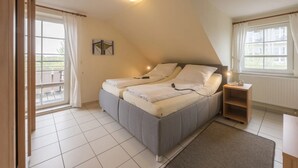 A bedroom with a bed, a nightstand, a window, and a view of the outside. - Apartment in Friedrichskoog-spitze With Parking Space (Friedrichskoog)