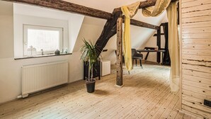 A loft-style room with a sloped ceiling, exposed wooden beams, a radiator, a potted plant, a table with chairs, and a window with a view. - Cosy Holiday Home in Sankt Goarshausen With Barbecue (Sankt Goarshausen)