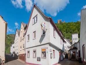 En traditionell europeisk byggnad med en skylt som visar att det är en restaurang, en trappa som leder upp till en övre våning och en utsikt över en kulle i bakgrunden.