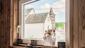 A window with a view of a building with a tower, a white door, and a shelf with decorative items. - Cosy Holiday Home in Sankt Goarshausen With Barbecue (Sankt Goarshausen)