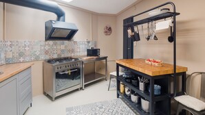 A compact kitchen with a gas stove, oven, and a black hanging rack with utensils. - Cosy Holiday Home in Sankt Goarshausen With Barbecue (Sankt Goarshausen)