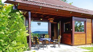 Una cabaña de madera con un patio, mobiliario exterior y vistas al paisaje.