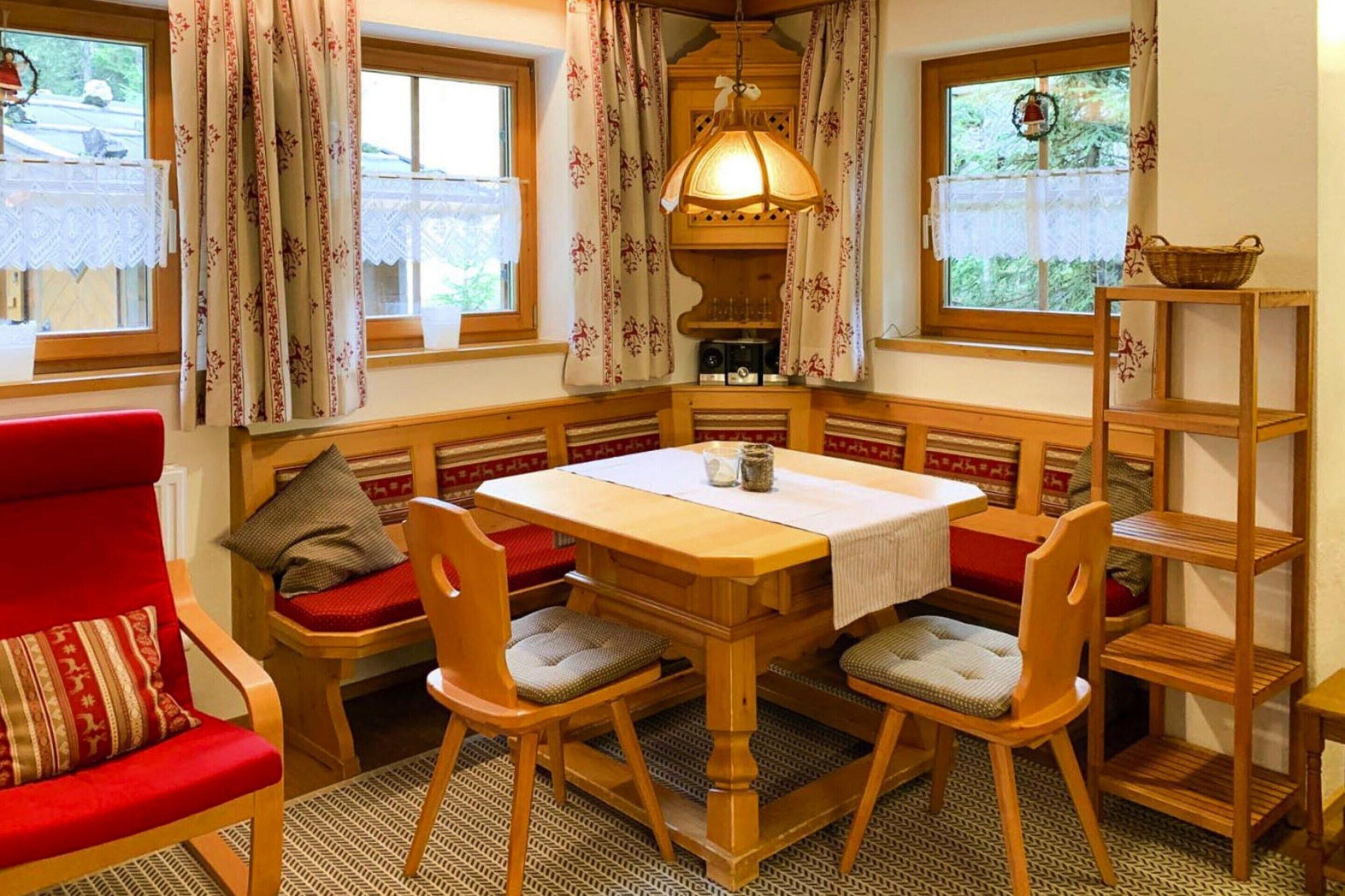 A cozy room with a wooden table, four chairs, a bench, and a bookshelf.