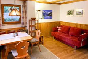 Una habitación acogedora con una mesa de comedor de madera, un sofá rojo y una ventana con vistas a las montañas.