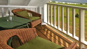 Eine überdachte Veranda mit Korbmöbeln, einem Tisch und Blick auf einen Fluss.