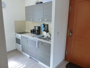 A compact kitchen with a built-in oven, a coffee maker, and a sink.
