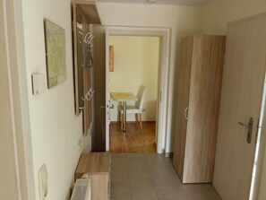 A hallway with a wooden door, a radiator, and a small table with chairs. - Apartment View of Fortress in Pirna (Pirna)