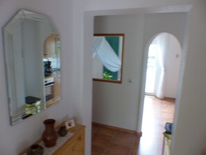 A hallway with a mirror, a wooden table with vases, and a tiled floor. - Apartment View of Fortress in Pirna (Pirna)