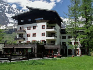 A multi-story hotel with balconies, surrounded by a mountainous landscape. - Contemporary Apartment in Breuil-cervinia Near Ski Area (Valtournenche)