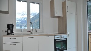A modern kitchen with white cabinets, a built-in oven, and a coffee maker. - Apartment in Steeg in a Beautiful Setting (Steeg)