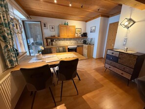 Una cocina acogedora con armarios de madera, una mesa de comedor con sillas y un mueble bajo con cajones.