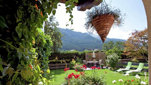 Un giardino con un'aiuola circolare, una recinzione in legno e un patio con mobili da esterno.