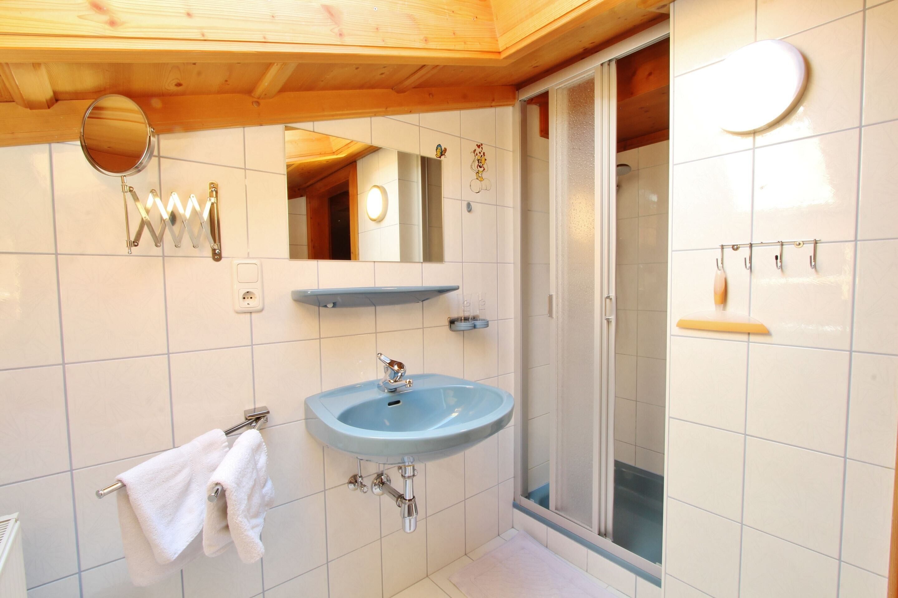 A bathroom with a blue sink, a mirror, a towel rack, and a shower area.