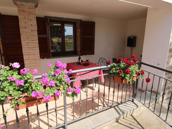 A balcony with a table set for two, potted plants, and a window with shutters. - Farmhouse With Pool in an Area With History, Nature and art (Bagnoregio)