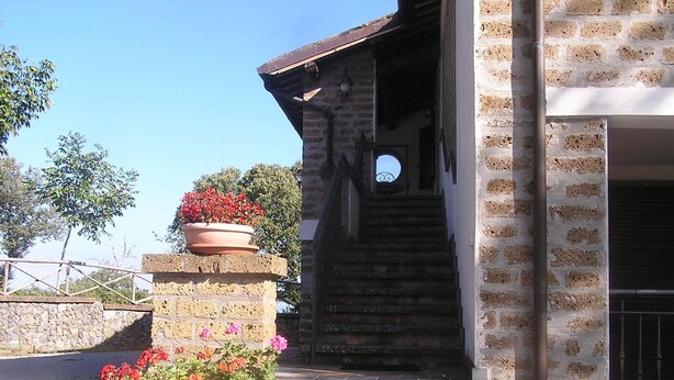 Una escalera de piedra que conduce a la entrada de un edificio con fachada de ladrillo y una puerta de metal.