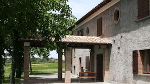 A covered outdoor area with a bench, a pergola, and a building with a stone facade and wooden shutters. - Farmhouse With Pool in an Area With History, Nature and art (Bagnoregio)
