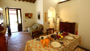 A dining area with a table set for two, featuring a floral tablecloth, plates, cutlery, and a bowl of fruit. - Farmhouse With Pool in an Area With History, Nature and art (Bagnoregio)