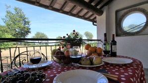 A table set with fruits, wine glasses, and plates on a balcony with a view of trees and a clear sky. - Farmhouse With Pool in an Area With History, Nature and art (Bagnoregio)