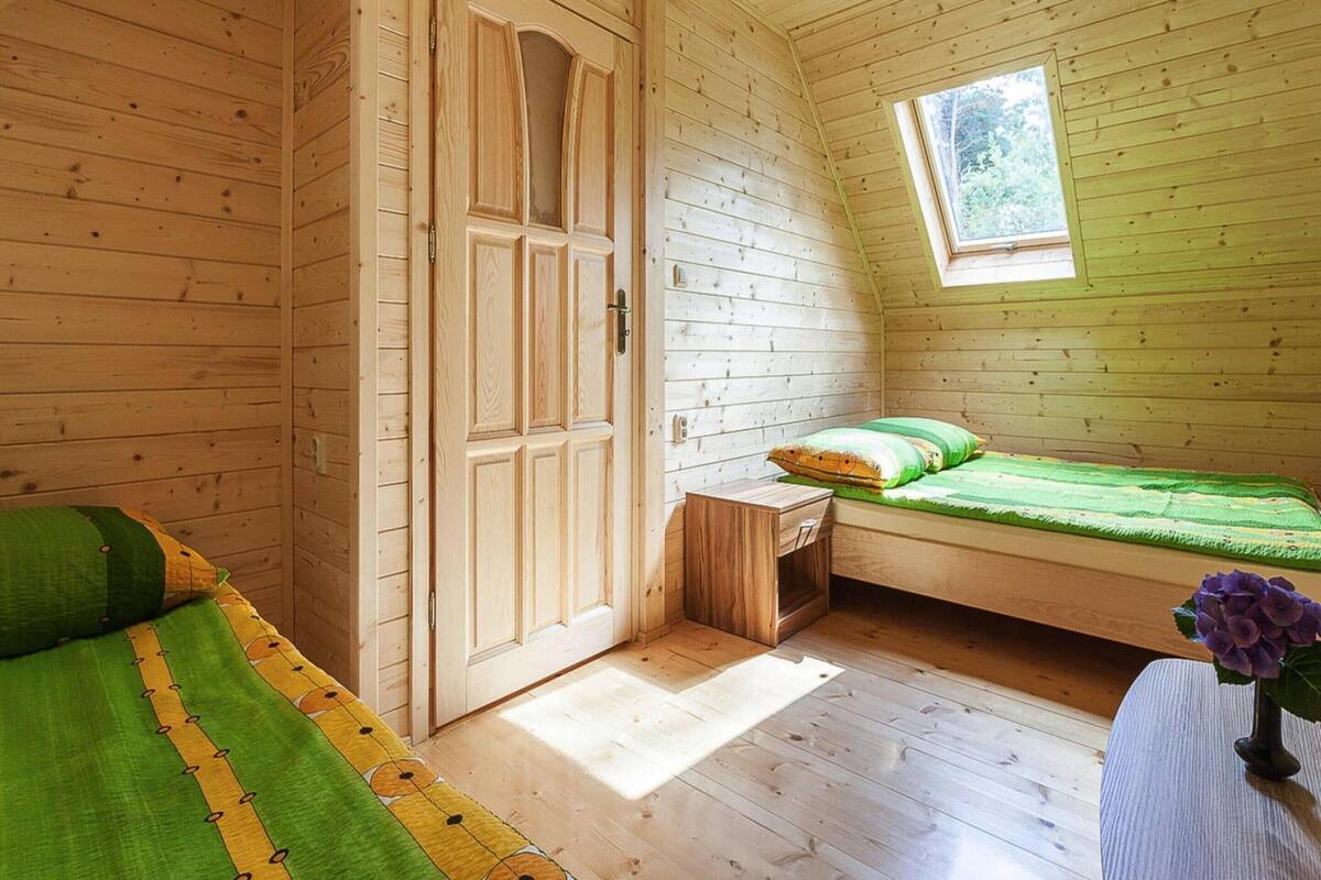 A cozy cabin room with a loft bed, a small wooden table, and a window.
