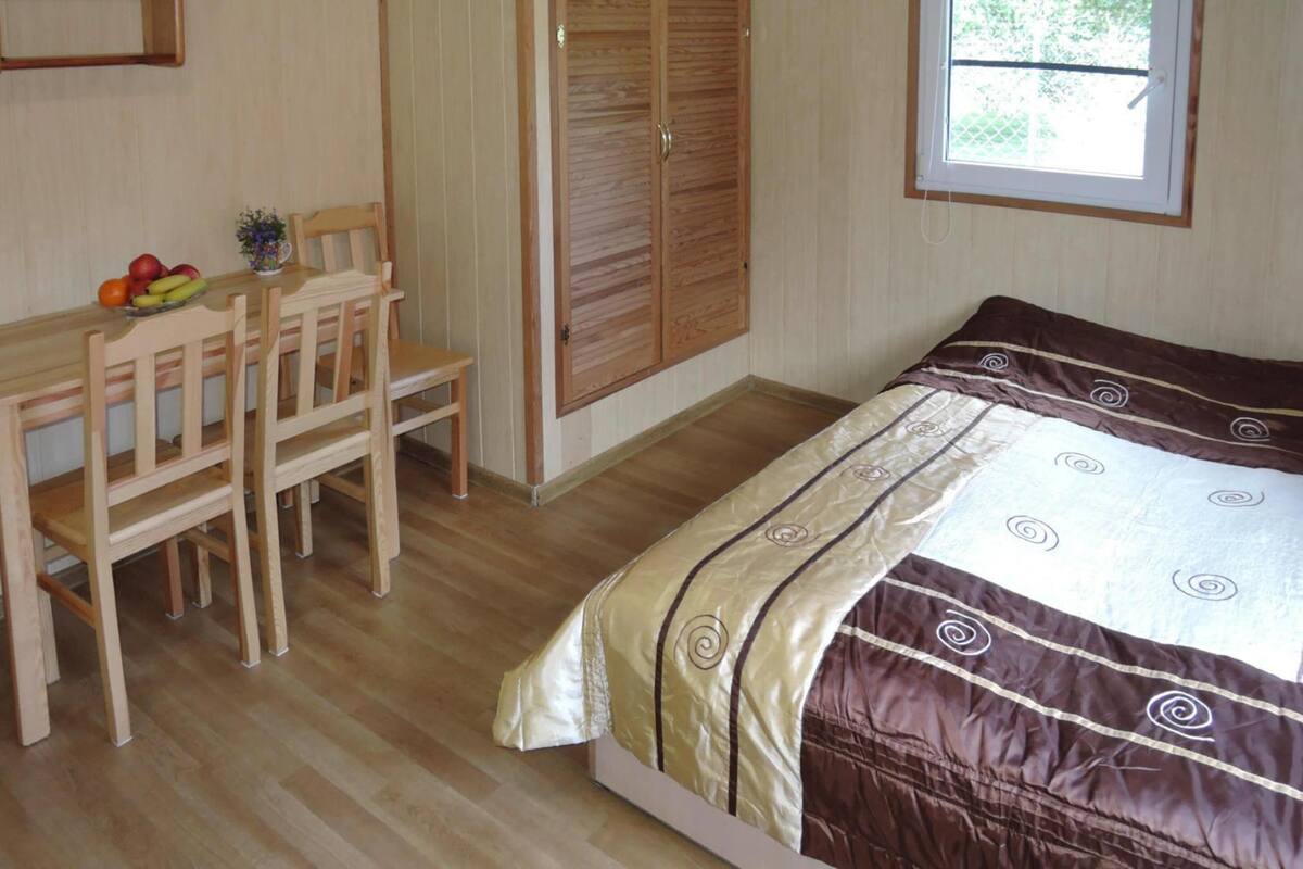 Une chambre à coucher avec un lit, un bureau avec des chaises, une armoire et une fenêtre.