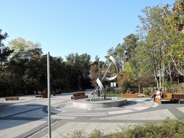 A public park with a central sculpture, benches, and trees. - Bungalows in Wrzosowo - The Bird's Cage for 4 Persons (Kamien Pomorski)