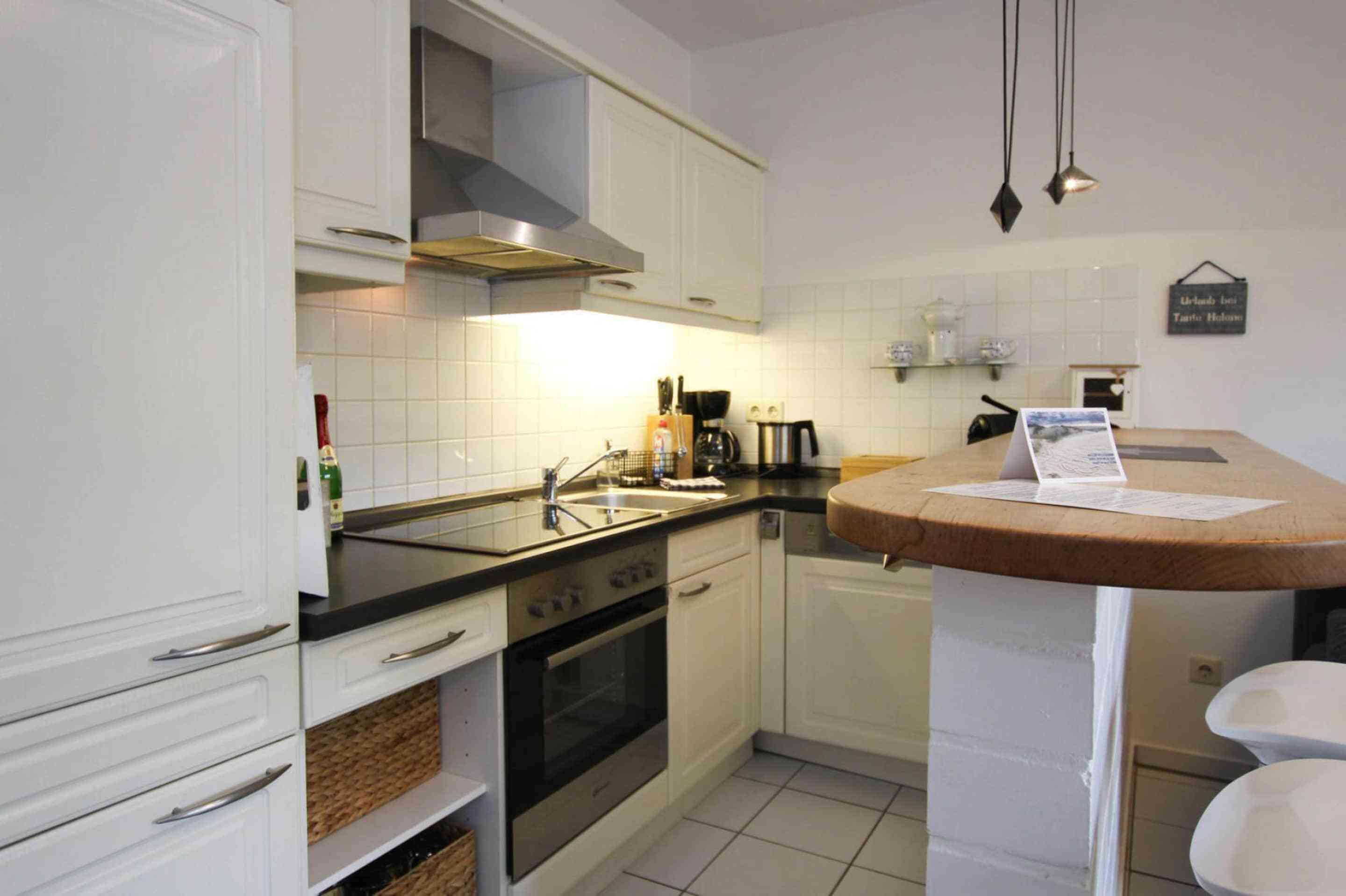 Una cocina con armarios blancos, una estufa, un fregadero y una encimera con un papel encima.