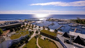 A marina with boats docked, a pier extending into the water, and buildings with green roofs. - Reihenhaus im Ostseeresort Dampland (Damp)