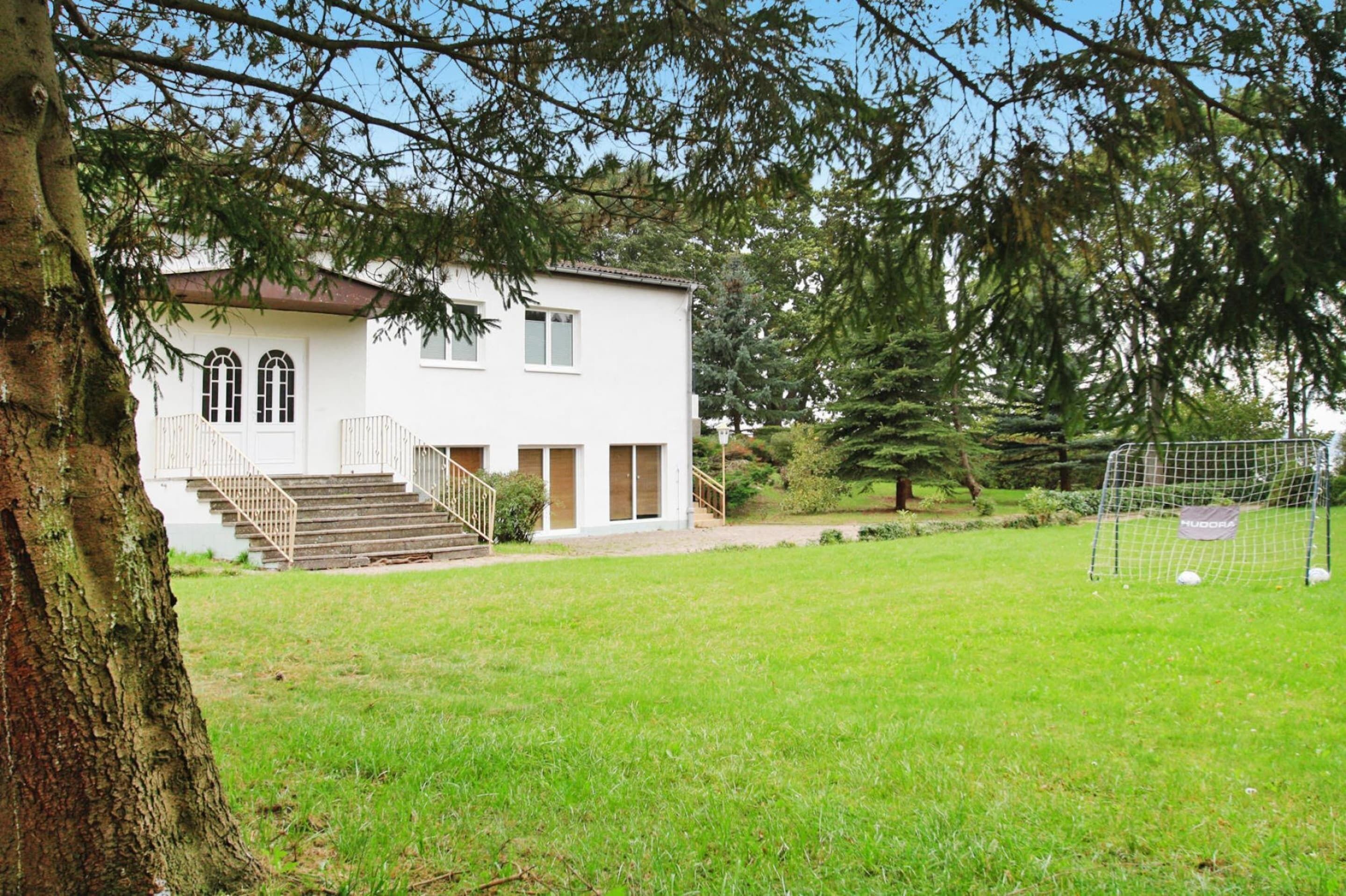 A white building with a staircase leading to a door, a grassy yard, and a soccer goal.