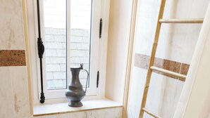 A bathroom with a bathtub, a window with a vase, and a towel rack. - Room for 2 or 3 people (Chemillé-en-Anjou)
