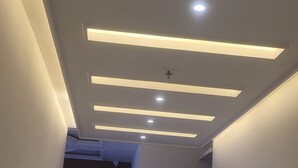 A hallway with a modern ceiling design featuring recessed lighting and linear light strips. - THE SHEHNAI RESORT (Alwar)