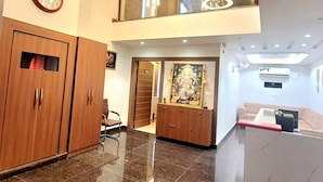 A lobby with a reception desk, a clock, a large mirror, and a statue. - THE SHEHNAI RESORT (Alwar)