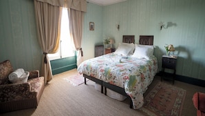 A bedroom with a bed, a nightstand, a chair, and a window with curtains. - Room for 2 persons (Chemillé-en-Anjou)