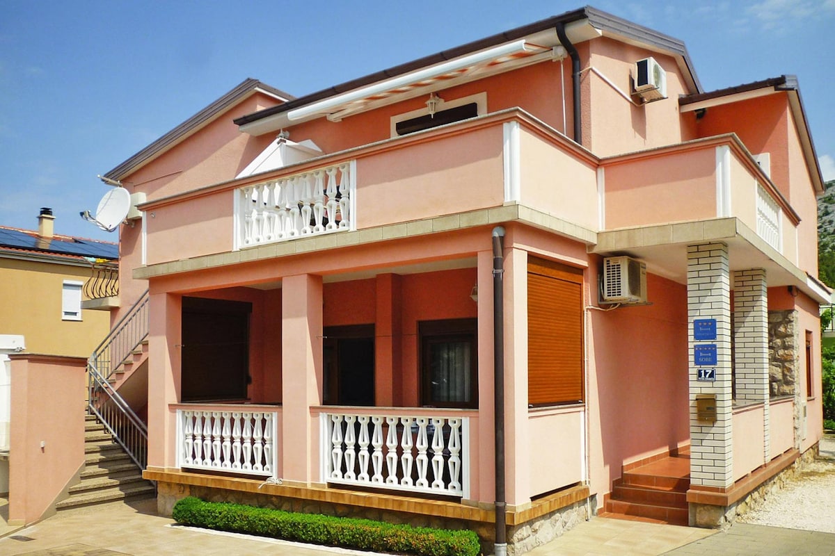 A two-story building with a balcony, a staircase, and a satellite dish.