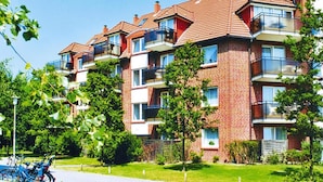 A multi-story residential building with brick exterior, balconies, and a well-maintained lawn. - Apartment in Cuxhaven With Community Pool (Cuxhaven)