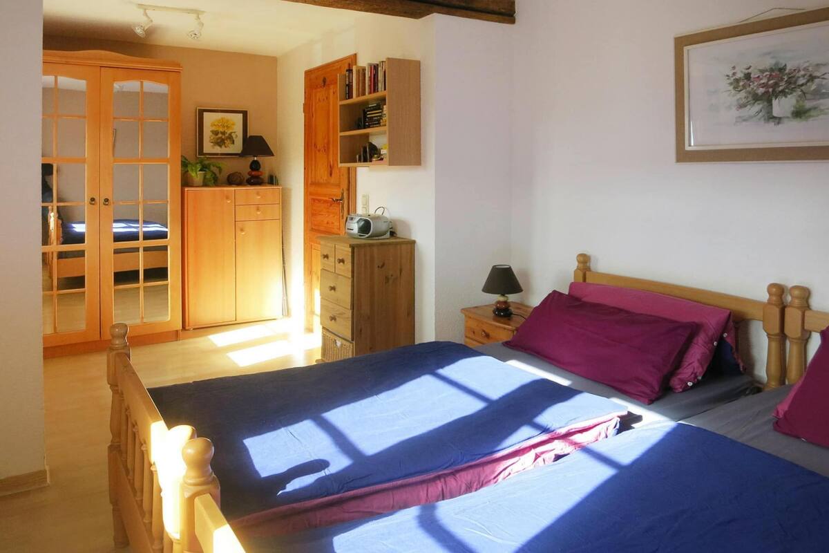 A bedroom with a bed, a wardrobe, a bedside table, and a nightstand.