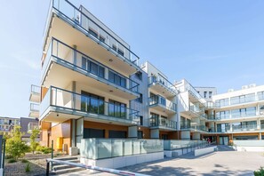 En fleretagers boligbygning med altaner, store vinduer og en gårdhave.