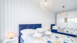 A modern hotel room with a large bed, a nightstand, a mirror, and a hanging light fixture. - Apartment Next to the Beach With sea View, Ustronie Morskie (Ustronie Morskie)