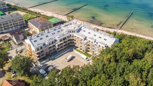 A multi-story hotel with a rooftop terrace, adjacent to a beach with clear waters and a pier. - Apartment Next to the Beach With sea View, Ustronie Morskie (Ustronie Morskie)
