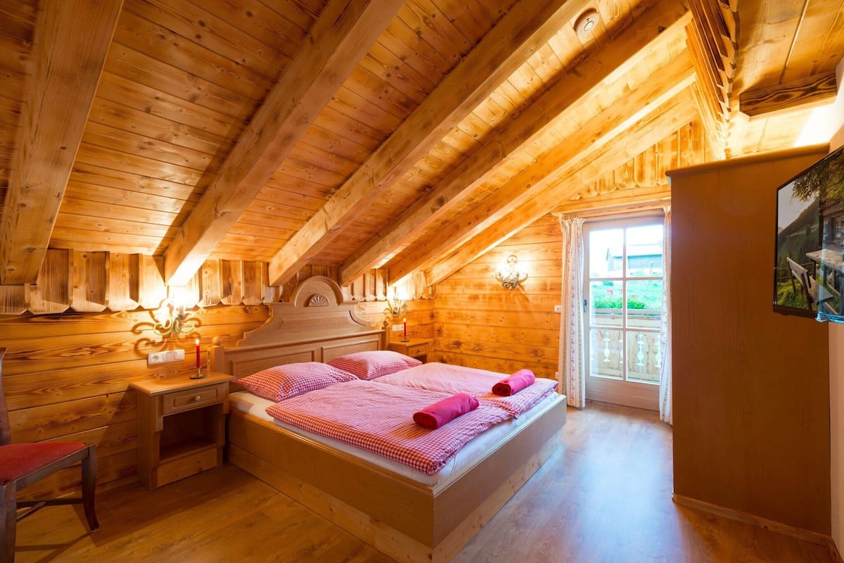 Une chambre dans une cabane en bois, avec un lit, une table de chevet et une fenêtre.